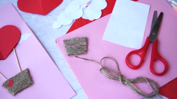 白い木のテーブルの上でバレンタインデーのための美しい手がグリーティングカードを作った — ストック動画