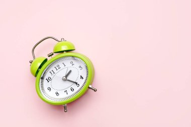 Fotokopi alanı olan pembe arkaplan üzerindeki yeşil alarm saati