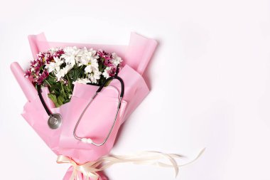 Beyaz arka planda bir buket çiçek ve steteskop. Ulusal Doktor Günü. Hemşire günün kutlu olsun. Kopyalama alanı olan üst görünüm