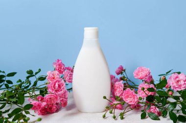 organik vücut losyonu ve mavi arka planda taze pembe çiçekler, şablon