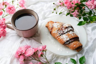 Kahvaltı kahvesi ve tatlı. Beyaz arka planda pembe güller.