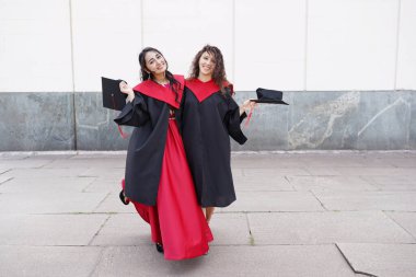 Üniversitenin yakınlarında açık havada şapka takan başarılı kız öğrencilerin portresi.