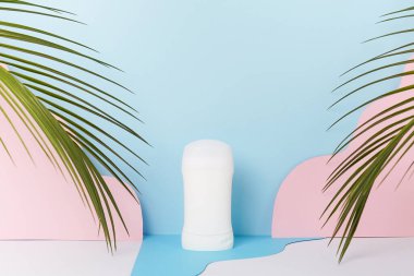 Mockup kozmetik deodorant, palmiye yapraklı mavi bir arka planda şişe ambalajı, vücut bakımı. Boşluğu kopyala