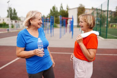Su şişeli iki kadın gülümsüyor. Kıdemli hanımlar dışarıda. Yeni aerobik eğitim programı