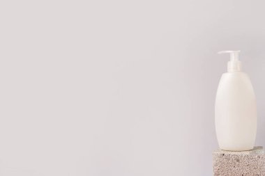 Gri arka plandaki taşın üzerinde duran şampuan ya da jöle beyaz şişe, kopyalama alanı. Krema, sabun, köpük için makyaj malzemesi