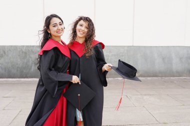 Üniversitenin yakınlarında açık havada şapka takan başarılı kız öğrencilerin portresi.