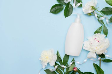 Beyaz çiçekler ve şampuan ya da mavi arka planda duş jeli. Güzel kadın konsepti. Düz yat, boşluğu kopyala