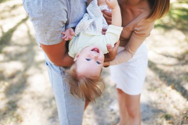 Mutlu genç aile birlikte vakit geçiriyor, anne ve baba dışarıda bebeğiyle yeşil doğada..