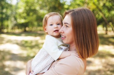 Açık havada mutlu ve uyumlu bir aile. Anne ve bebeği, yazın doğada oynuyorlar.