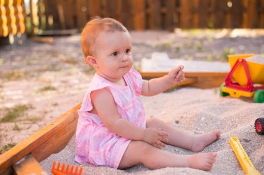 Oyun sahasında kum havuzunda kumla sevimli bebek oyunu