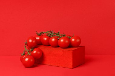 Kırmızı zemin üzerinde yeşil saplı bir avuç domates. Yatay, ön görünüm.