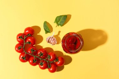 Sarı arka planda fesleğen ve biberli ev yapımı DIY doğal domatesler