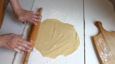 Kadınların elleri hamuru beyaz masada yoğurur.