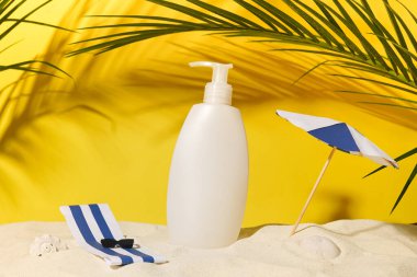 Kağıt şemsiyeli, güneş gözlüklü ve yeşil palmiye yapraklı yaz yolculuğunda şampuanlı ya da duş jöleli beyaz şişe. Hassas cilt ve vücut losyonu için nemlendirici güneş kremi