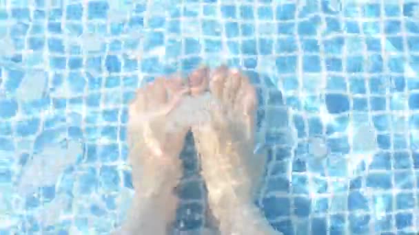 若い女性のクローズアップ足はリラックスして楽しい時間を過ごしてプールサイドに座って 足は純粋な水で屋外スイミングプール — ストック動画
