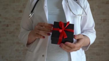Kadın doktorların ellerinde kırmızı kurdele olan hediye kutusu, Noel, Kara Cuma, doğum günü