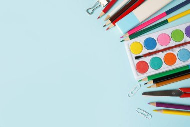 Mavi arka planda okul malzemelerinin genel görüntüsü.