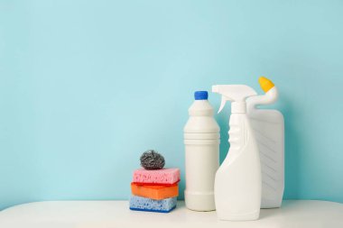 Mavi arkaplan üzerinde beyaz temizlik tüpleri ve süngerler seti metin için boş alan