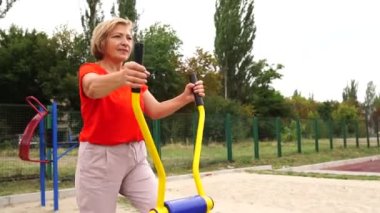 Aktif, olgun bir kadın stadyumda çeşitli ekipmanlarla çalışıyor.