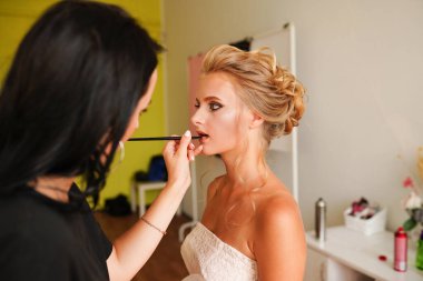Makyaj sanatçısı, güzellik salonunda çalışan model yüz fırçasına kozmetik uyguluyor. Kadın vizör makyaj ustası. Müşteri görünümüne yüz makyajı yapıyor.