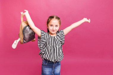 Pembe arka planda okul çantası olan şirin bir okul kızı.