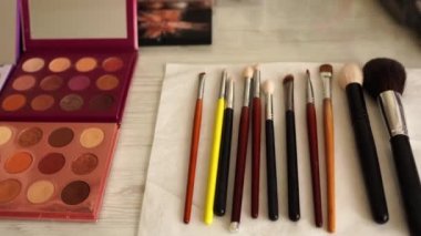 Makyaj fırçaları ve kozmetik ürünleri güzellik salonundaki masa arkasında.