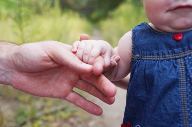 Aile parkın akşam ışığında. Mutlu bir aile kavramı. Ebeveynler bebeğin elini tutar..