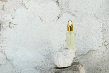 Cam şişedeki doğal kozmetik yağı ve üzerinde pipet makinesi taşın üzerinde duruyor. Organik kozmetik ürünler, cilt güzelliği ve sağlık konsepti..