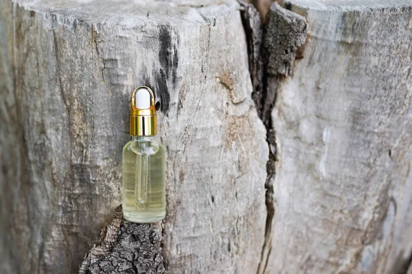 Glass cosmetic bottle with hyaluronic acid on the wood. Moisturizer cream or liquid. Hydrating serum, vitamin for face skin. concept of natural cosmetics, natural essential oil