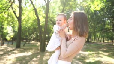 Açık havada mutlu ve uyumlu bir aile. Anne ve bebeği, yazın doğada oynuyorlar.