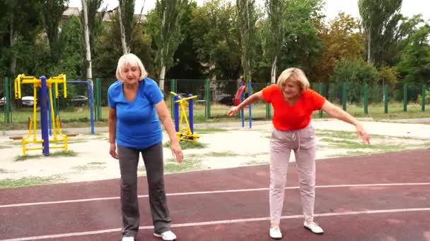 58歳と64歳の2人の成人女性がスタジアムの屋外で練習をしています — ストック動画
