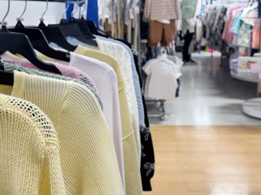 Pastel süveter ve örgü bluzları askılarda düzgünce sergilenen bir elbise rafı.