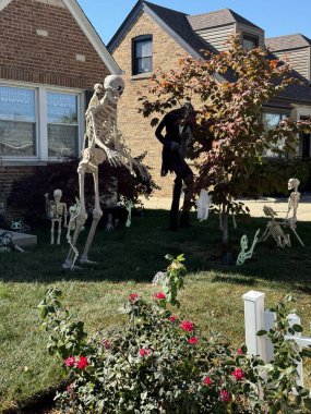 Güneşli bir sonbahar gününde Cadılar Bayramı için iskeletler ve ürkütücü figürlerle süslenmiş bir ev.