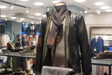 Moda mağazasında deri ceket ve eşarp giyen şık erkek mankeni.