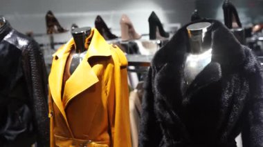 Moda mankenleri şık siyah kürklü ve sarı ceketli butikte sergileniyor.