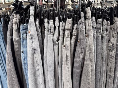 Mavi ve gri farklı tonlarda dar bir sıra kot sıradan bir moda mağazasında asılı duruyor.