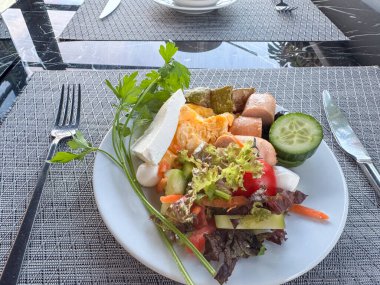 Sehpada sebze salatası, peynir, salatalık ve sosis.