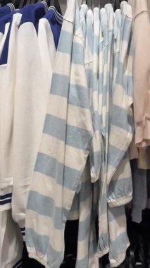 Açık mavi ve beyaz çizgili süveter askısı diğer pastel ve lacivert giysilerin arasında birbirine yakın duruyor.