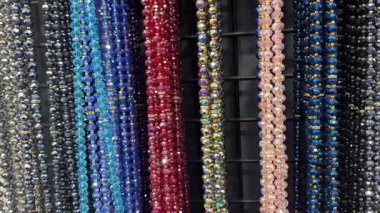 Parlak renkli boncuklar sergilenen dikey iplikçiklerde asılı.