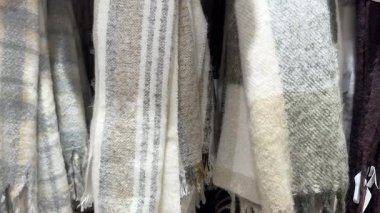 Bir çift yumuşak ekose ve çizgili eşarp dilsiz bej ve gri renkler birlikte asılı.