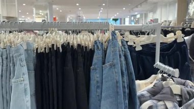 Kot pantolon ve siyah pantolon mağazada yan yana asılı.