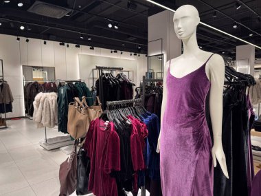 Modern bir moda mağazasının içinde mor kadife bir elbise giymiş bir manken var.