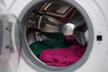 Modern cephede dönen renkli kıyafetler çamaşır makinesi davulları yüklüyor.