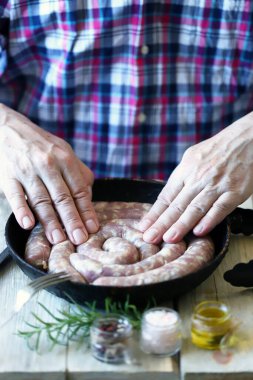 Şef tavaya çiğ sosis koyar. Bavyera sosisi pişiriyorum. Bir erkek şef tavaya çiğ sosis koyuyor..