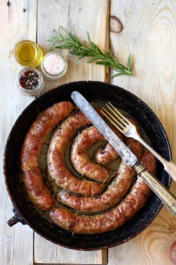 Ahşap bir masada tavada ev yapımı sosis. Kırsal biçim.