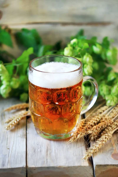 A glass of wheat beer on a wooden surface. Wheat and hops. Beer concept.