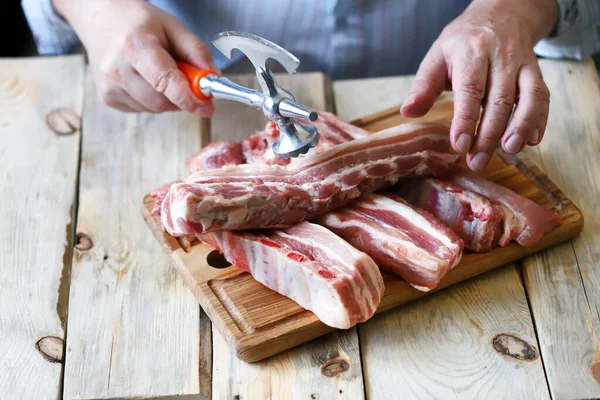 The chef cuts raw pork ribs with a hatchet. Cooking meat.