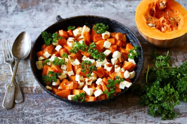 Tavada peynir ile pişirilmiş balkabağı parçaları. Sıcak balkabağı salatası. Sonbahar yemekleri..