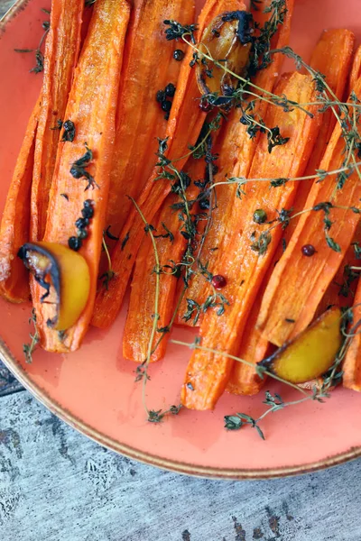 A plate with baked carrots. Macro. Baked carrots in strips with herbs and spices. Vegan diet. Vegan lunch recipe idea.