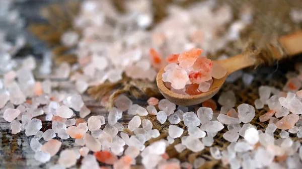 Coarse grains of Himalayan salt in a wooden spoon.
